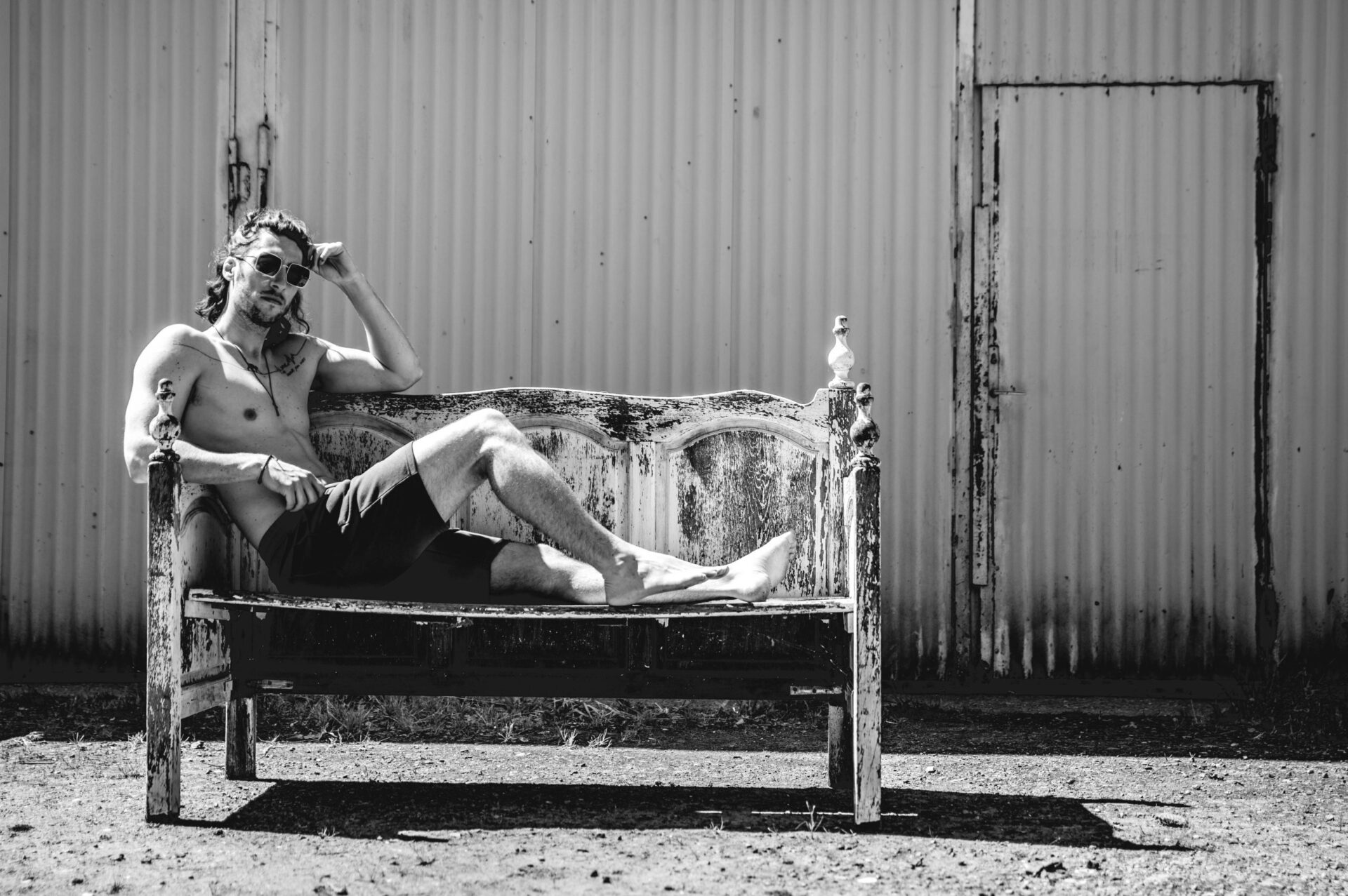Man zit op bankje als model bij hangar aan kanaal in Heusden-Zolder (Barnoe) - Black & White photography